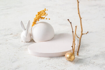 Composition with podiums, tree branches, Easter egg, bunny and mimosa flowers on light background - obrazy, fototapety, plakaty