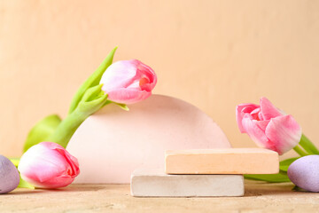 Composition with podiums, Easter eggs and tulip flowers on color background, closeup