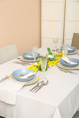 Festive table setting with eggs, bunnies and mimosa flowers served for Easter celebration