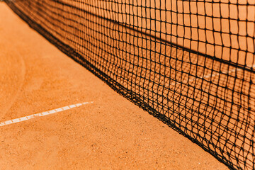 Light orange empty outdoor clay court surface dry grungy ground baseline detail for playing tennis with net in sunny day, gravel texture background, copy space for text inscription banner
 - obrazy, fototapety, plakaty