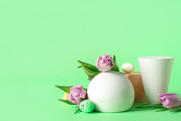 Podiums with Easter eggs and tulips on green background