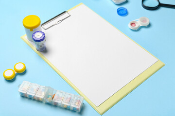 Blank clipboard with ophthalmologist's supplies on blue background. World Health Day
