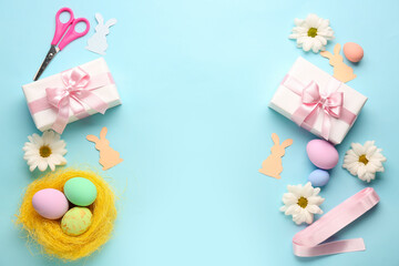 Frame made of gifts, Easter eggs, paper rabbits and flowers on blue background