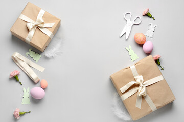 Frame made of gifts, Easter eggs, paper rabbits and flowers on grey background