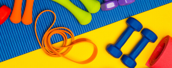 set of multicolored fitness equipment accessories.fitness equipment dumbbells scales expander jump rope for banner background.
