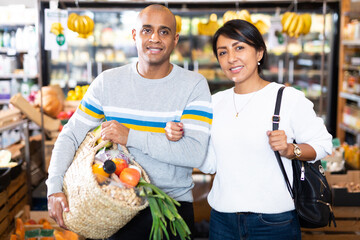 Portrait of happy couple with bag full of groceries in supermarket interior