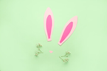Paper bunny ears and gypsophila flowers on green background