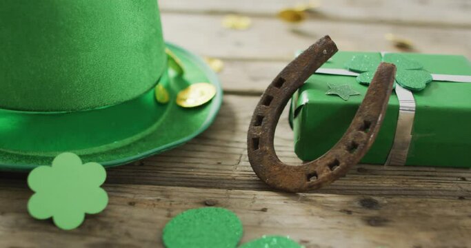 Shamrocks and green hat with horseshoe over coins with copy space on wooden table