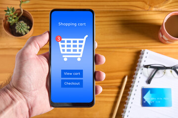Hand holding mobile phone with online store interface