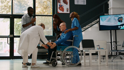 Young man and woman helping old adult to attend checkup consultation, bringing sick patient with...