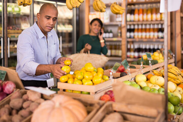 Buyer carefully selects ripe tangerines in a grocery supermarket