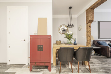 Solid wood dining table next to a red Asian style sideboard in a room with solid wood pillars