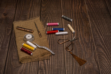 Still life with spools of thread of various colors together with a piece of cheesecloth, a tape measure and vintage copper scissors