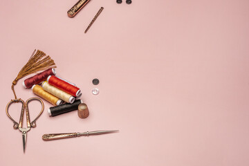 Still life with spools of thread of various colors together with some old-style copper scissors with other accessories in the same style
