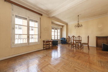 Living room of a house with a few loose wooden furniture, some chairs, a round table and old white wooden windows © Toyakisfoto.photos