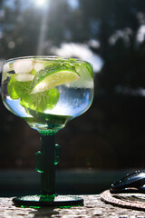 close up of cold mojito cocktail with limes at pool with sunglasses and straw hat