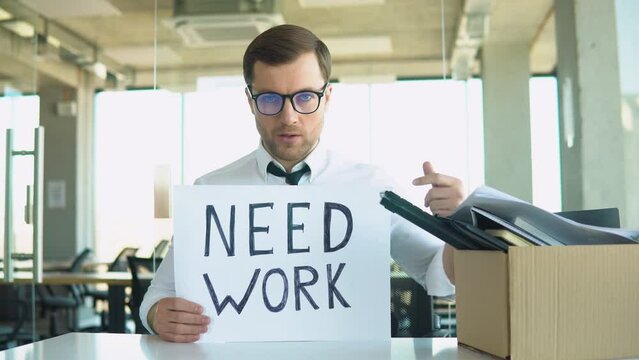 Dismissed worker holding cardboard sign poster Need work. Sad depressive distressed young guy suffers from anxiety, sadness because of losing job or business
