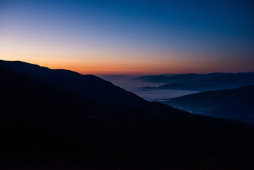 Mountain range with visible silhouettes through the morning colorful fog