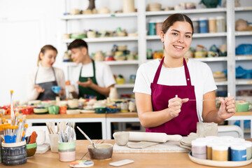 Fototapeta premium Young woman in apron modeling clay pottery in workshop