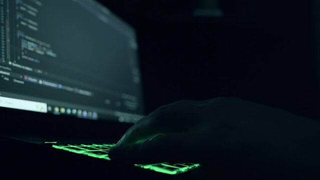 male programmer writes program code on a laptop. close-up. night.