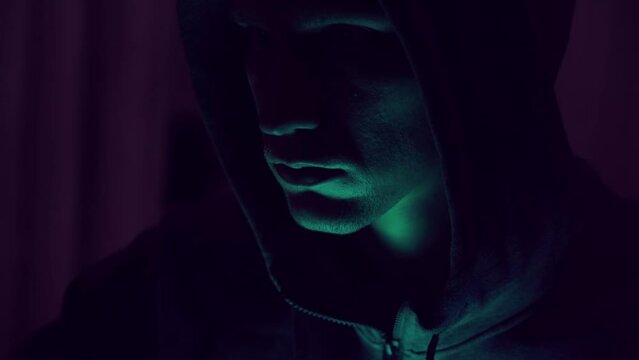 Portrait of an intimidating male hacker in a hood. nervous look. close-up.