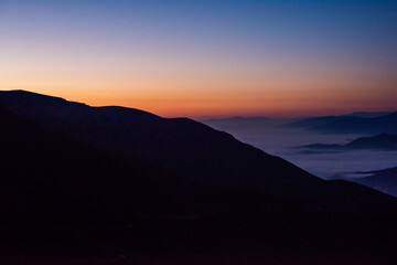 Mountain range with visible silhouettes through the morning colorful fog