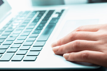 Manicured hand on blue laptop keyboard