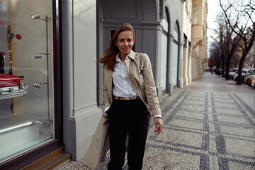 Obraz premium Fashionable woman crossing the city street and looking at camera. High quality photo