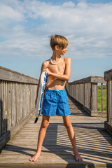 Young Preteen Boy Standing on Boardwalk with Boogie Board at the Beach