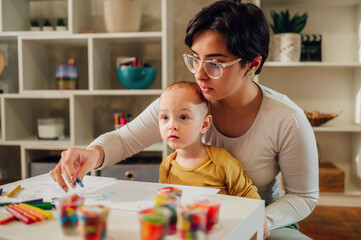 Fototapeta premium Mother and son drawing with crayons at home and creating art