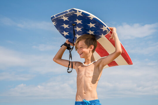 Youth Child Preteen Boy Standing on Beach Holding A Boogie Board Over His Head