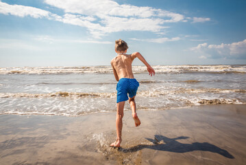 Youth Child Preteen Boy Running Into the Waves and Ocean Water at the Sunny Beach