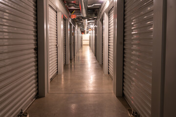 Interior climate controlled rental storage units with exit signs. Looking down a hallway with...