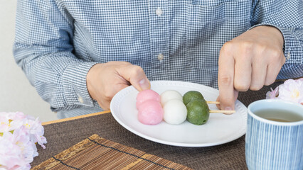 三色団子と桜｜和菓子を食べる男性