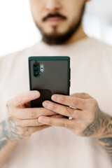 Closeup of asian man hands holding mobile phone shopping online, ordering food from home, selective focus. Handsome hipster with stylish tattooed hands reading text message. Technology concept 