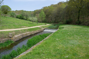 River walk along the Rato river in Lugo, Galicia, with lots of green vegetation and blue sky in April. Spain.