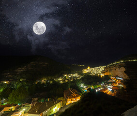 Panoramic view of the medieval village of Alcala del Jucar at night and with full moon. Albacete, Spain. 