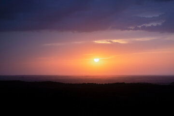 Obraz premium eautiful panoramic view of the sky with the orange sun in the sunset between clouds.