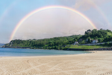 Getaria beach in Gipuzkoa (Basque Country, Spain) with cloudy sky and a rainbow on the horizon. 