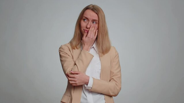 Upset disappointed businesswoman wipes tears and cries from despair, being sad because of unfair things. Female girl in formal suit in depression, despair, loss. Pretty woman on gray studio background