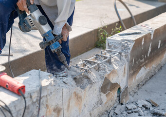 Worker using electric hammer drill to cut the wall concrete.