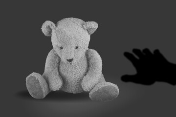 Toy bear and hand shadow, child abuse concept