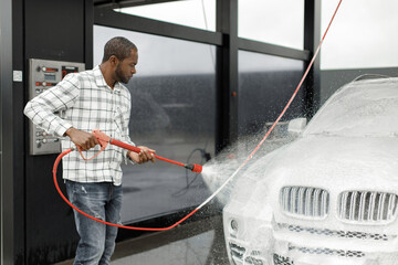 Middle aged black man cleaning his car outside in the car wash