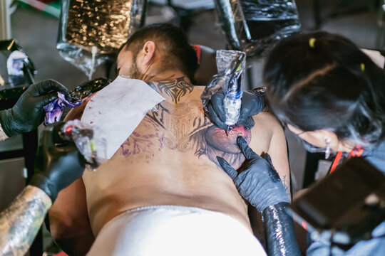 man and woman tattoo artists performing a fusion art of coloring and whip shading
