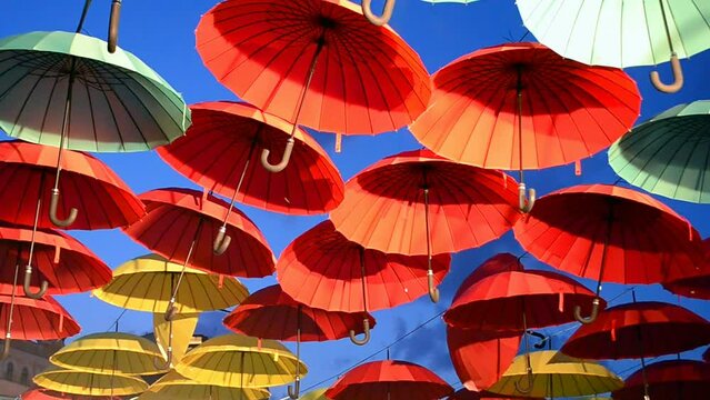 rainbow red and yellow umbrella heap on blue sky in sunny day, multicolor parasol diversity