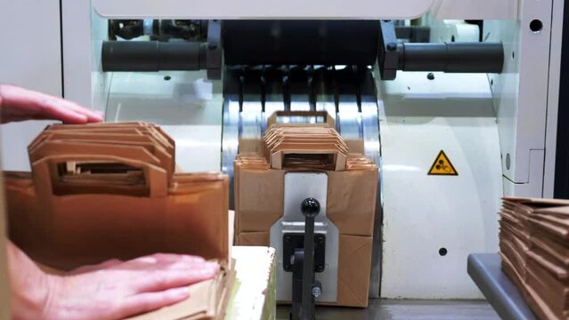 A machine for the production of household paper bags. Eco-friendly packaging. Laying of finished packages on the conveyor.