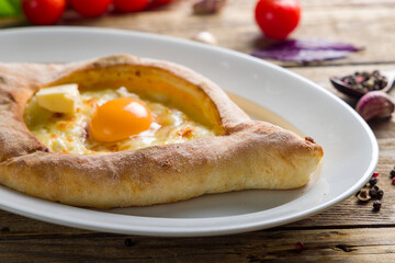 ajara Khachapuri with cheese, egg and butter, georgian kitchen on wooden table macro close up