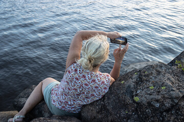 Blonde woman taking a photo with a smartphone