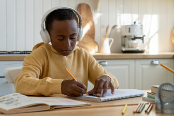 Focused kid African American boy sitting at desk working on engineering project, child using drafting tools ruler and pencil doing geometry homework, while studying at home. Technical drawing for kids
