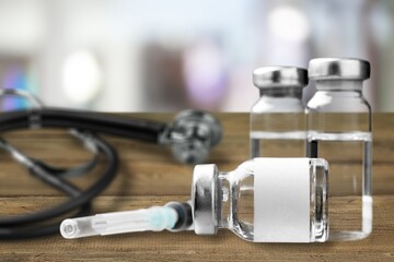 Bottles of medical vaccine vials with stethoscope on desk